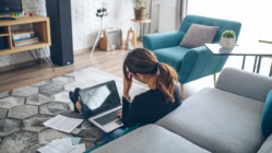 Serious concentrated young woman sitting on floor in living room while checking credit card debt bills at home