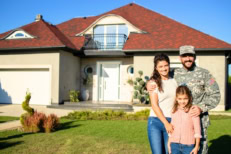 A military family standing in front of their new home.