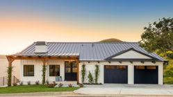 A single family home with a metal roof and black garage doors