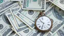 a pocket watch is sitting on top of a pile of dollars