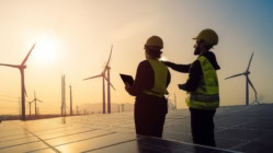 Engineers inspecting solar panels and wind turbines at a renewable energy farm during sunset, symbolizing clean energy and sustainability"