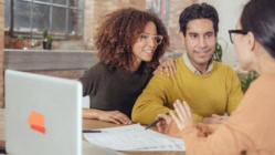 Happy couple meeting with a mortgage advisor to discuss home loan options and credit score requirements for buying a house.