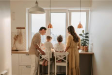A family grouped up together looking out the window.