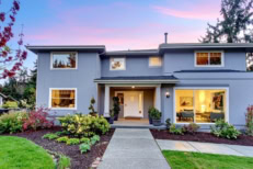 Modern two-story single-family home with landscaped yard and large windows at dusk, representing residential real estate and homeownership.