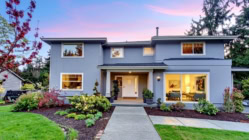 Modern two-story single-family home with landscaped yard and large windows at dusk, representing residential real estate and homeownership.