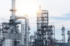 Large oil refinery and industrial energy facility with pipelines and processing towers, representing global oil supply and energy markets