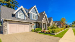 Modern suburban single-family homes with stone exterior, two-car garages, and landscaped front yards.