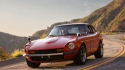 Red vintage sports car driving on a winding mountain road during golden hour, symbolizing road trip travel and automotive lifestyle.