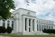 Exterior view of the U.S. Federal Reserve building in Washington, D.C. with American flag, representing central banking, monetary policy decisions, interest rates, inflation control, and economic outlook.