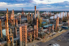 Large oil refinery and industrial processing plant with pipelines, storage tanks, and smokestacks producing energy, representing global oil production, energy industry infrastructure, fuel supply, and economic impact on inflation and interest rates.