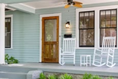 A nice picture of the front of a house showing the door, windows, and 2 rocking chairs outside