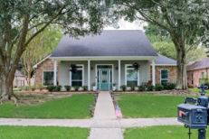 A front view of an Acadian renovated home with columns, sidewalks and a colorful front door recently purchased with the changing real estate market.