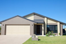 Front of a new modern single story family home with green grass and clear blue sky for copy space.