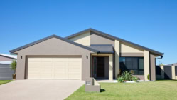 Front of a new modern single story family home with green grass and clear blue sky for copy space.