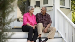 Old couple talking to each other on the stairs outside of their home