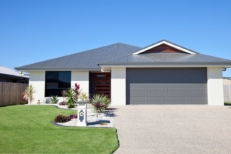 Simple looking house with a garage, clean lawn, and the blue sky behind it
