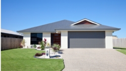 Simple looking house with a garage, clean lawn, and the blue sky behind it