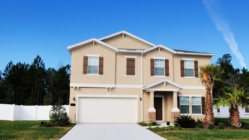 Picture of a House with trees and green grass. House has a garage